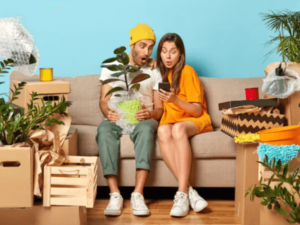 una coppia su un divano con piante in mano e introno scatoloni