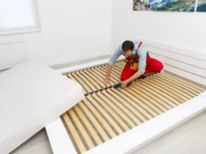 un operaio monta un letto con doghe in legno