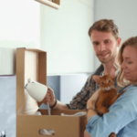 una coppia tiene in braccio un gatto mentre disfano scatoloni