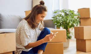 una donna seduta a terra in un soggiorno con degli scatoloni intorno